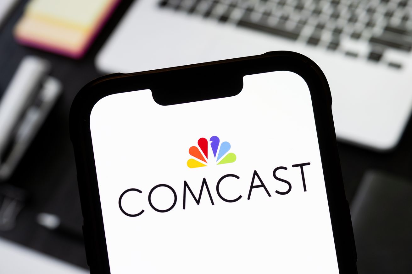 In this photo illustration, a Comcast logo is seen displayed...